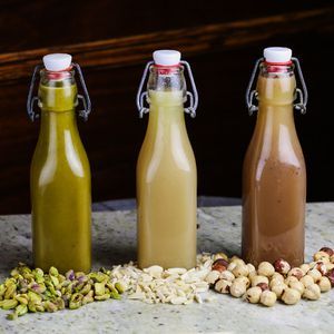 kolm lahtikäivat pudelit orgeat (pistaatsia, mandel ja sarapuupähkel) pähklihunnikute taga