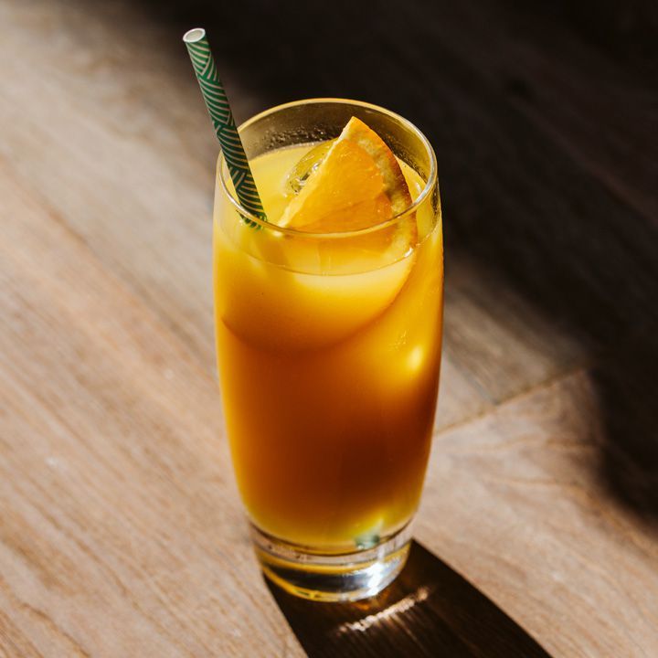 Cocktail de nombril flou dans un verre highball avec une paille verte et blanche