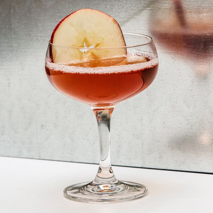 Вашингтонски ябълков коктейл в чаша купе, гарниран с резен ябълка