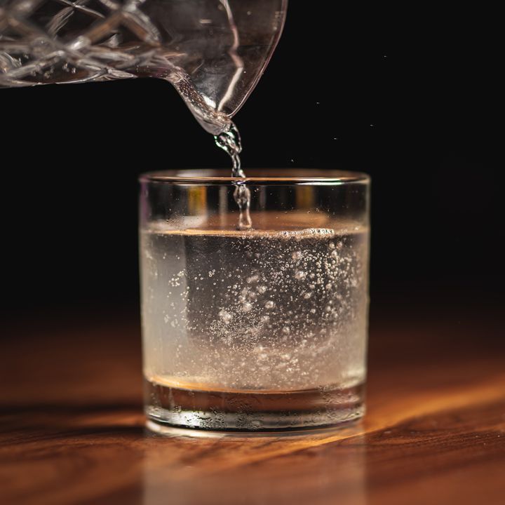 Viskoz, ipeksi bir kokteyl, süssüz bir kayalık camdaki kristal berraklığında bir buz küpünün üzerine dökülürken hafifçe kabarcıklar. İçecek, zifiri siyah bir arka plana dönüşen sert ahşap üzerine oturur.