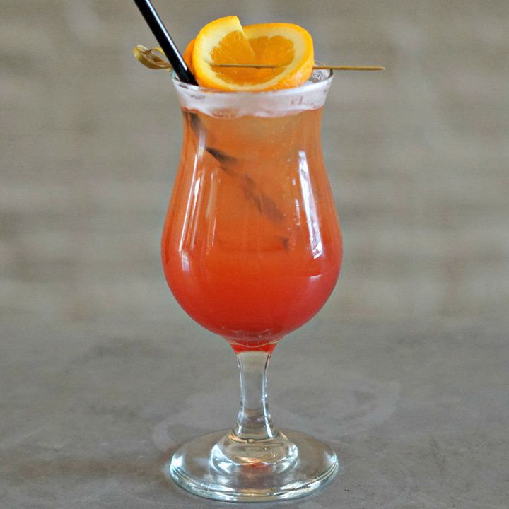 Ένα κόκκινο χρώμα Spritz σε ένα ποτήρι τυφώνα, γαρνιρισμένο με πορτοκαλί τροχό σε μια επιλογή