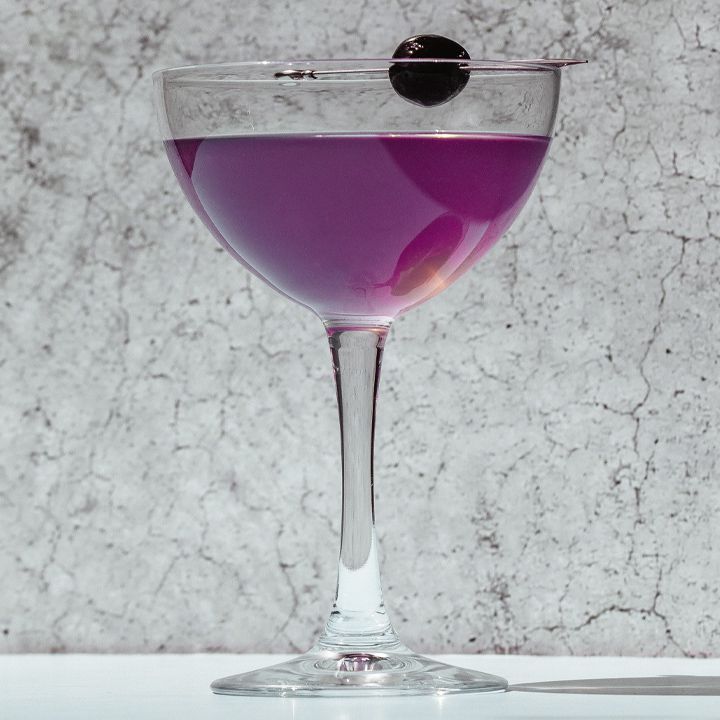 Purple-hued Aviation cocktail i en kupé med kirsebærgarnering