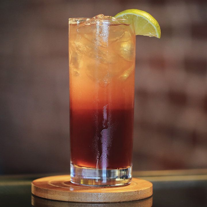 Cocktail el diablo avec un quartier de lime, servi sur un dessous de verre en bois